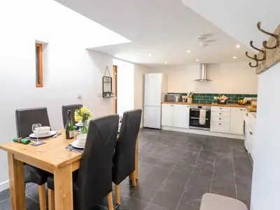 a kitchen and dining room with a wooden table and chairs at Ysgubor Craig Y Gronfa in Machynlleth