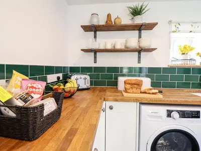 a kitchen with a washing machine and baskets of bread at Ysgubor Craig Y Gronfa in Machynlleth