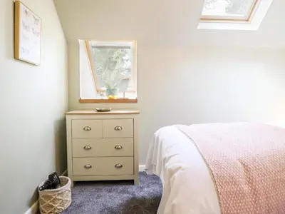 a bedroom with a bed and a dresser with a window at Ysgubor Craig Y Gronfa in Machynlleth