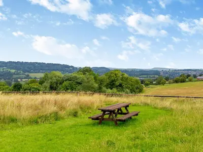 a wooden picnic table in a field of grass at The Stables in Forden