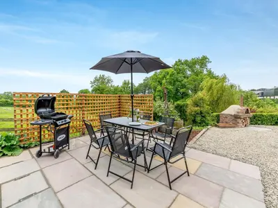 a table and chairs with an umbrella and a grill at The Cider House in Clee Saint Margaret
