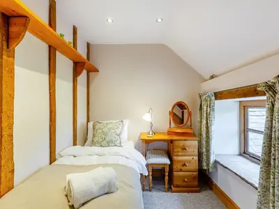 two beds in a room with a desk and a window at The Cider House in Clee Saint Margaret