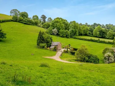 an old house in a field of green grass at The Cider House in Clee Saint Margaret