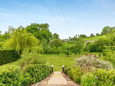 a path through a garden with bushes and trees at The Cider House in Clee Saint Margaret