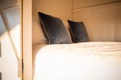 a bed with two black pillows on top of it at Canvas & Campfires, Luxury Safari Tent Glamping, only Seren Tent has a hot tub in Lampeter