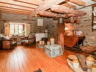 a living room with wooden floors and a stone wall at Halls Mill in Kington