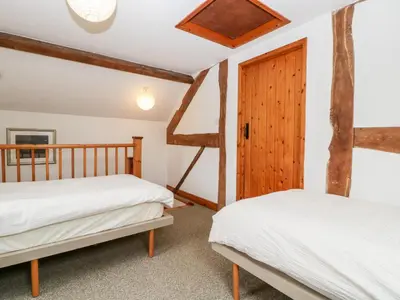 a bedroom with two beds and a wooden door at Halls Mill in Kington