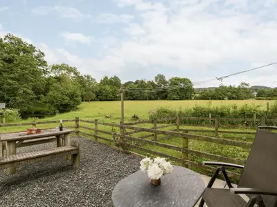 a patio with a table and a fence with a field at Halls Mill in Kington