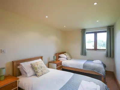 a bedroom with two beds and a window at Y Dderwen in Pen-y-bont-fawr