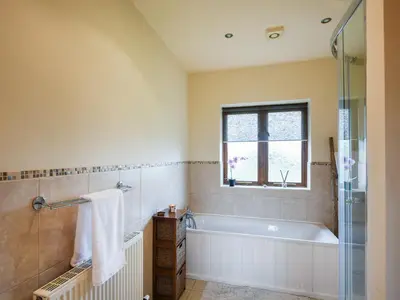 a bathroom with a tub and a window at Y Dderwen in Pen-y-bont-fawr