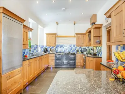 a large kitchen with wooden cabinets and stainless steel appliances at Rockcliffe in Aberdyfi