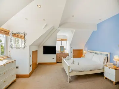 a bedroom with a white bed and a tv at Rockcliffe in Aberdyfi