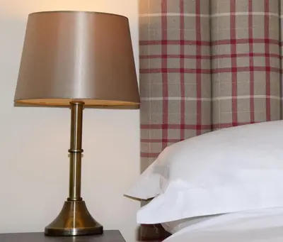 a lamp sitting on a table next to a bed at The Mulberry Inn in Glyn-Ceiriog