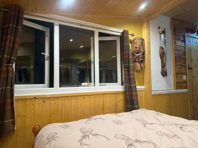 a bedroom with a window with a mask on the wall at Cuckoo Cabin, Tyn Y Cwm in Scyborycoed