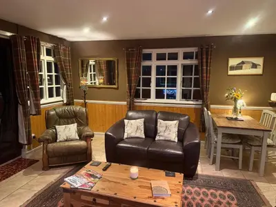 a living room with two chairs and a table at Cuckoo Cabin, Tyn Y Cwm in Scyborycoed
