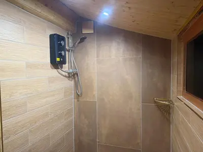 a shower stall in a bathroom with a shower at Cuckoo Cabin, Tyn Y Cwm in Scyborycoed