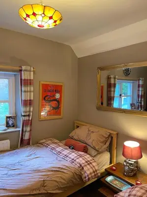 a bedroom with a bed and a mirror and a table at Bear Cottage, Tyn Y Cwm in Scyborycoed