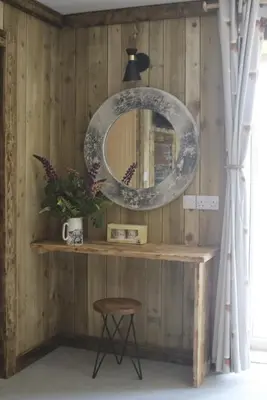 a mirror on a wall with a table and a stool at The Moo-tel at Moody Meadows in Aberaeron