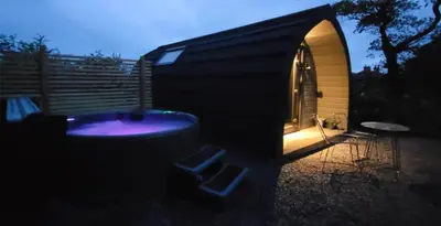 a black building with a hot tub in a yard at Odli Glamping - Deri in Welshpool
