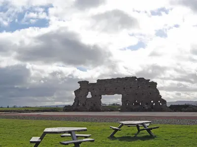 two picnic tables in front of a stone building at Walkmill Lodge in Wentnor