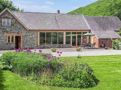 a stone house with a garden in front of it at Mashers Barn in Bucknell