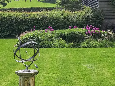 a statue in the middle of a yard with flowers at Mashers Barn in Bucknell