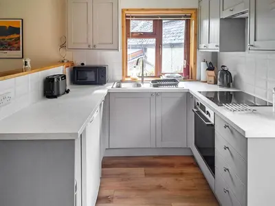 a white kitchen with white cabinets and a sink at Garden Lodge in Llanvair Waterdine