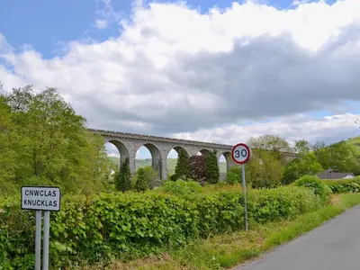 a train bridge over a road with a sign at Garden Lodge in Llanvair Waterdine
