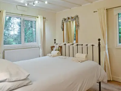 a bedroom with a bed with white sheets and windows at The Summer House in Easthope