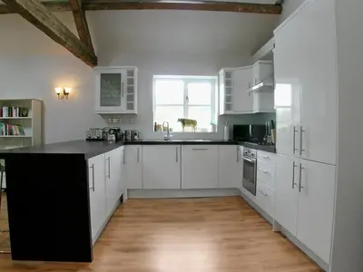 a kitchen with white cabinets and a black counter top at Cow Shed in Farden