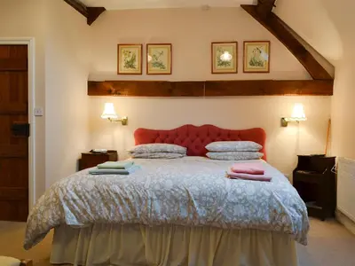 a bedroom with a large bed with a red headboard at Stoke Court Farm Barn in Stoke Saint Milborough