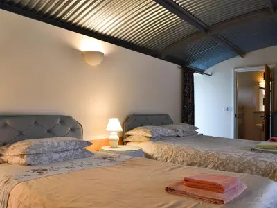 a bedroom with two beds and a lamp on a table at Stoke Court Farm Barn in Stoke Saint Milborough