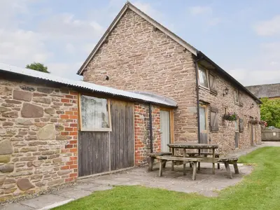 a picnic table in front of a brick building at Stoke Court Farm Barn in Stoke Saint Milborough