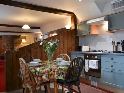 a kitchen with a table with a vase of fruit on it at Stoke Court Farm Barn in Stoke Saint Milborough