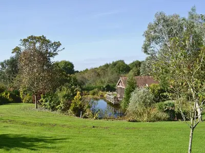 a house in the middle of a field next to a lake at Angel Barn in Farden