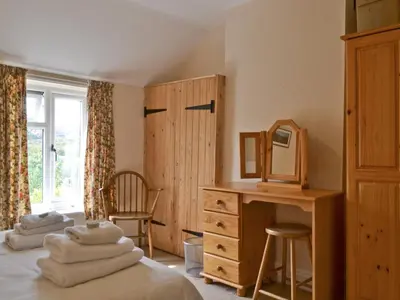 a bedroom with two beds and a desk and a mirror at Honeysuckle Cottage in Minsterley