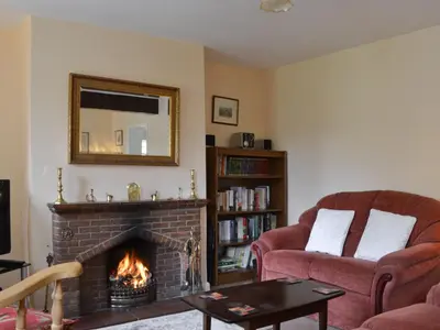 a living room with a fireplace and a mirror at Honeysuckle Cottage in Minsterley