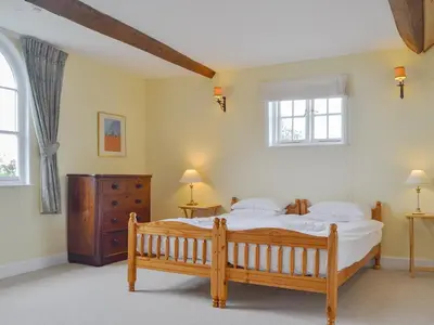 a bedroom with a wooden bed and two windows at Cronkhill Farmhouse in Wroxeter