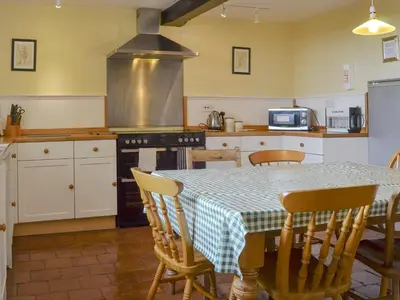 a kitchen with a table and chairs and a kitchen with a stove at Cronkhill Farmhouse in Wroxeter