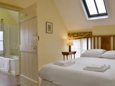 a bedroom with a bed and a bathroom with a tub at Cronkhill Farmhouse in Wroxeter