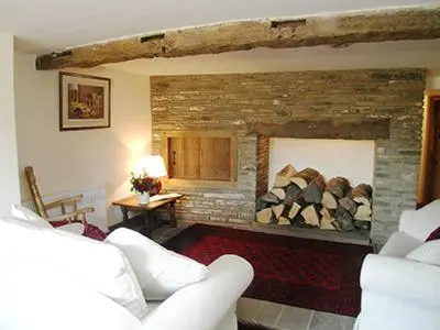 a living room with a stone fireplace with white furniture at Mouse Castle Barn in Hay-on-Wye