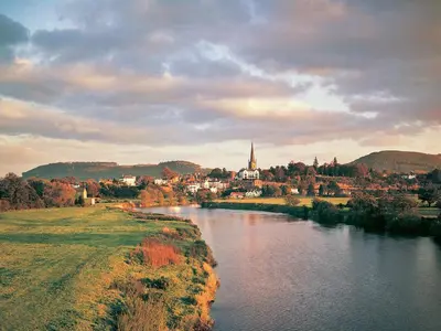 a river with a town and a church in the distance at Mouse Castle Barn in Hay-on-Wye