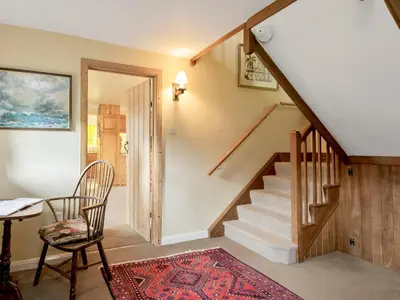a room with a staircase with a chair and a table at Walnut Tree Cottage in Bucknell