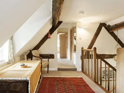 a living room with a table and a staircase at Walnut Tree Cottage in Bucknell