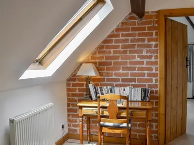 an attic room with a desk and a brick wall at The Stables in Eardisland