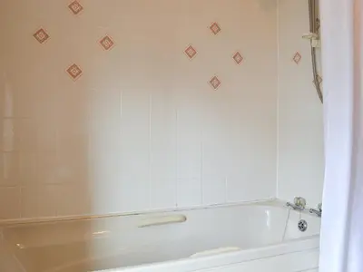 a bath tub in a bathroom with white tiles at The Cider Mill Cottage in Orleton
