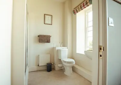 a bathroom with a toilet and a sink and a window at Stone House Wales in Kington