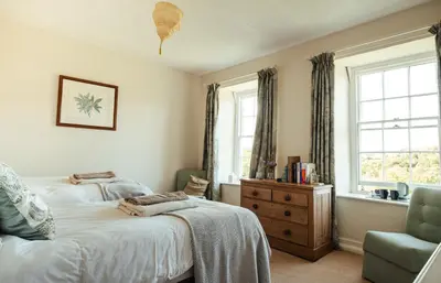 a bedroom with two beds and a chair and windows at Stone House Wales in Kington
