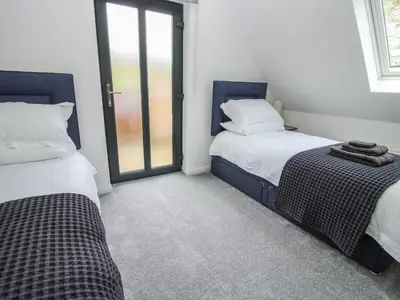 a bedroom with two beds and a window at The Larches in Bishops Castle