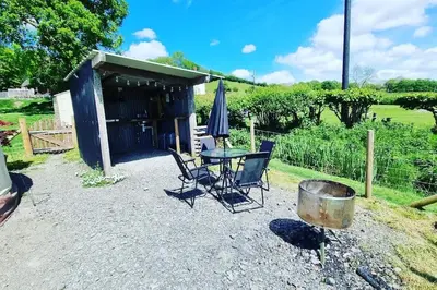 a patio with a table and chairs and an umbrella at Bronfelen Yurt in Cynghordy